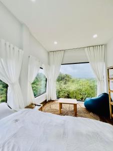 een slaapkamer met een bed en een groot raam bij Măng Đen Land - Homestay&Coffee in Kon Von Kla