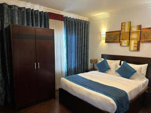 a bedroom with a bed with blue and white pillows at Blue Meadows-NuwaraEliya in Nuwara Eliya