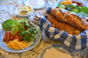 una mesa con un plato de comida con pan y una ensalada en ペンション イメージハウス, en Hara