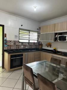 Una cocina con una mesa de cristal y sillas. en Casa Al Mare, en Itanhaém