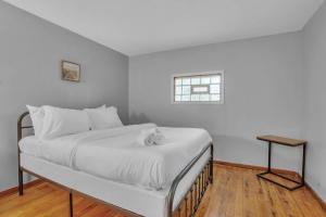Cama en habitación blanca con ventana en Park Place Suites, en Buffalo