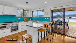 a kitchen with white cabinets and a view of a deck at Bermagui River View - Unit 1,1 Lindo Street 3 bdrm Villa in Bermagui