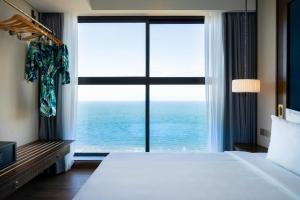 a bedroom with a large window with the ocean at Mandala Cham Bay Mui Ne in Phan Thiet