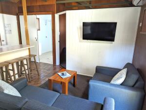 a living room with two blue couches and a television at Gumnut Glen Cabins in Yeppoon