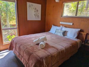 a bedroom with a large bed with two towels on it at Gumnut Glen Cabins in Yeppoon