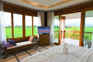 1 dormitorio con 1 cama y balcón con TV en แลภู ดูนา LaePhu DooNa Resort and Restaurant, en Ban San Pa Sak