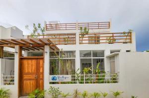a white house with a wooden door and a balcony at Raalhu Fonu Maldives in Mahibadhoo