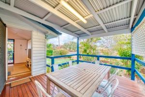 a porch with a wooden table and white chairs at Sandy Feet Cottage in Bargara