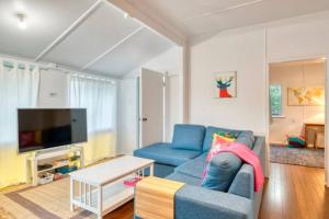 a living room with a blue couch and a tv at Sandy Feet Cottage in Bargara
