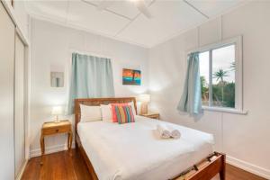 a bedroom with a bed and a window at Sandy Feet Cottage in Bargara