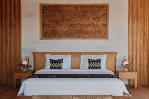 um quarto com uma cama grande e lençóis brancos em TUNAK Resort Lombok em Bumbang