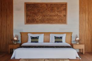 ein Schlafzimmer mit einem großen Bett mit weißer Bettwäsche in der Unterkunft TUNAK Resort Lombok in Bumbang