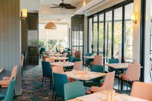 um restaurante com mesas, cadeiras e janelas em Mercure Gold Coast Resort em Gold Coast