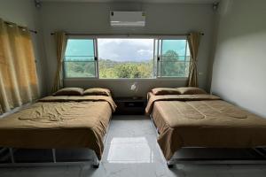 2 Betten in einem Zimmer mit Fenster in der Unterkunft Family Hill Khaokho บ้านพัก กางเต็นท์ วิวภูเขา in Khao Kho
