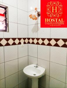 baño con lavabo blanco y letrero rojo en Hostal Plaza de la Concordia, en Santa Cruz de la Sierra