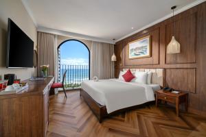 Dormitorio con cama, escritorio y TV en Golden Lotus Luxury Hotel Danang, en Da Nang