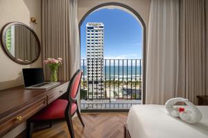 Habitación de hotel con escritorio y ventana con vistas. en Golden Lotus Luxury Hotel Danang en Da Nang