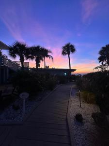 a pathway with palm trees and a sunset in the background at The Pearl Beach Inn in Englewood