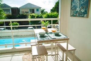 una mesa con 2 vasos de zumo de naranja en el balcón en Appartemment T2 cosy et spacieux : l’Oasis urbaine, en Les Abymes
