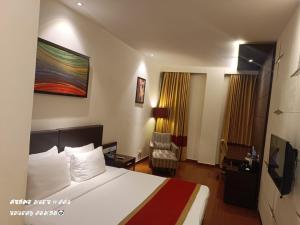 een hotelkamer met een bed en een stoel bij Hotel Borderland in Amritsar