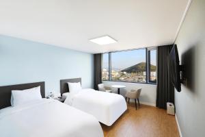 a hotel room with two beds and a window at Mokpo Ocean Hotel in Mokpo
