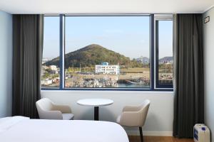 a bedroom with a large window with a view of a harbor at Mokpo Ocean Hotel in Mokpo