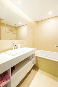 een badkamer met een witte wastafel en een bad bij Lynn House Metropolis 2Bedrooms Cozy - nearLotte Daewoo in Hanoi