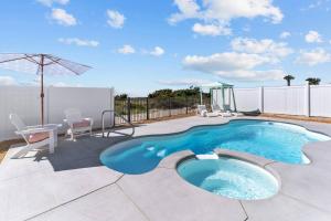 a swimming pool on a patio with chairs and an umbrella at SeaSons at the Point in Oak Island