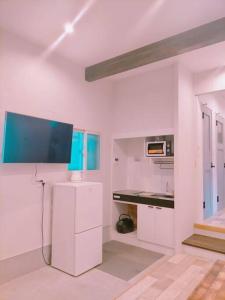 uma cozinha com armários brancos e uma televisão na parede em LILY's House em Sano