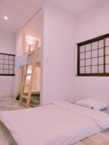 um quarto branco com uma escada e uma cama em LILY's House em Sano