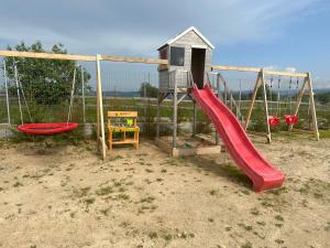 a playground with a red slide and a play structure at Mariseltinyhouse in Mărişel