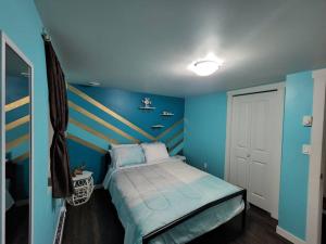 a blue bedroom with a bed with a striped headboard at TheAuroras: Vibrant&Cheerful 2 bdrm Stylish suite in Saskatoon