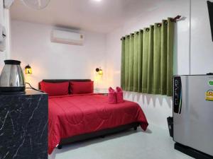 a bedroom with a red bed with green curtains at Baan Sabaijai Viking Home in That Phanom