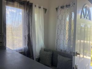 a kitchen with a table and a window with curtains at Ihola's Nest in Carriacou