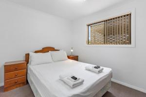 biała sypialnia z łóżkiem i oknem w obiekcie Costello Hotels - Moonta Bay Cabins w mieście Port Moonta