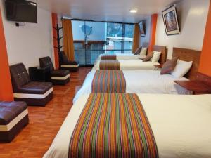a hotel room with four beds and a flat screen tv at Amakonkay Machupicchu in Machu Picchu