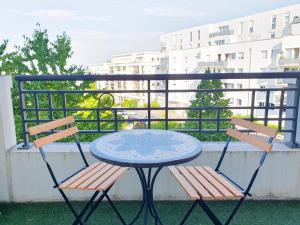 einen Tisch und zwei Stühle auf einem Balkon in der Unterkunft EXIGE HOME - Charmant 2 pièces Vue Tour Eiffel in Châtillon