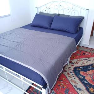 1 dormitorio con cama con sábanas azules y alfombra en Singgah Homestay en Kuala Terengganu