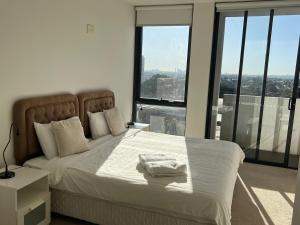 a bedroom with a large bed with white sheets and windows at Hurstville New apartment with city view in Sydney