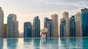 a woman in a infinity pool with a city skyline at Luxurious 2BR apt with panoramic Marina view in Dubai