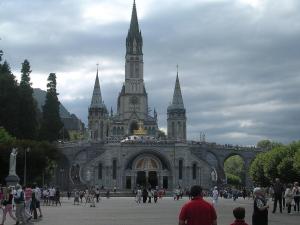 a large building with people walking in front of it at Hôtel du Château Fort in Lourdes