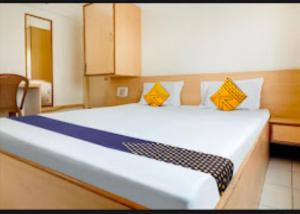a bedroom with a large bed with yellow and blue pillows at Hotel Rahi,Nashik in Nashik
