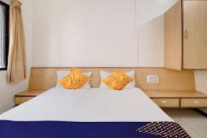 a bedroom with a large white bed with orange pillows at Hotel Rahi,Nashik in Nashik
