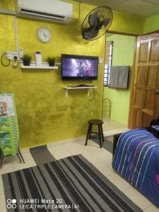 a bedroom with a tv on a yellow wall at LS ROMESTAY in Kangar