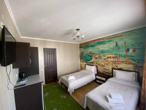Chon-Sary-OyにあるАрт-отель ololoFamilyのベッド2台が備わる客室で、壁には絵画が飾られています。