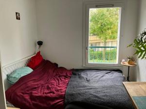 a bed in a room with a window at Maison de ville 102m2 3 chambres in Montigny-le-Bretonneux