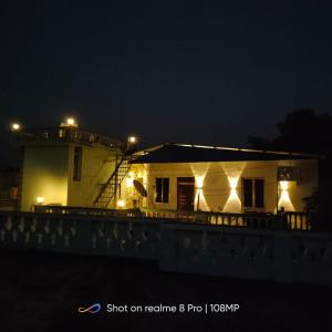 a house with lights on the side of it at night at Urban Sky in Shānti Niketan