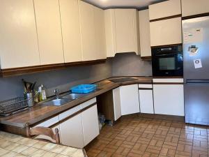 La cuisine est équipée de placards blancs, d'un évier et d'un réfrigérateur. dans l'établissement Maison de ville 102m2 3 chambres, à Montigny-le-Bretonneux