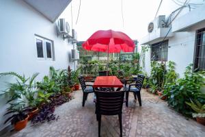 uma mesa vermelha e cadeiras com um guarda-sol vermelho em Seethala Bed & Breakfast em Pondicherry
