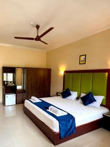 a bedroom with a large bed with a green headboard at Hotel Riverside in Baga